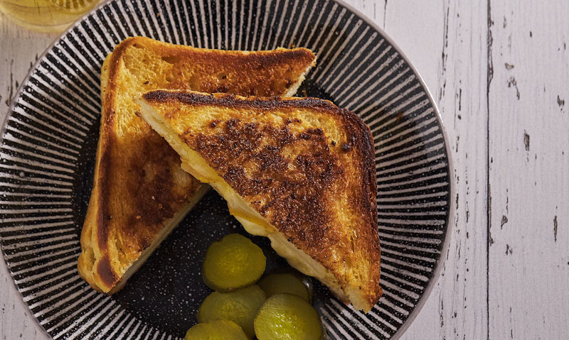 Serving of sliced pickles with grilled cheese sandwich