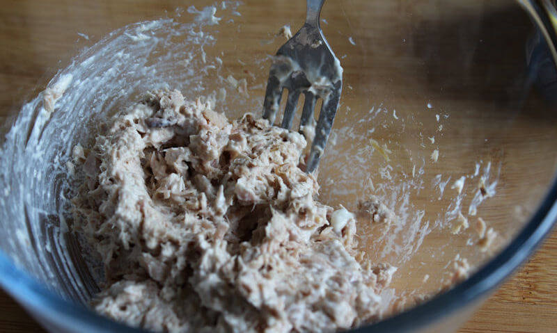 Tuna and mayonnaise thoroughly mixed in bowl with fork