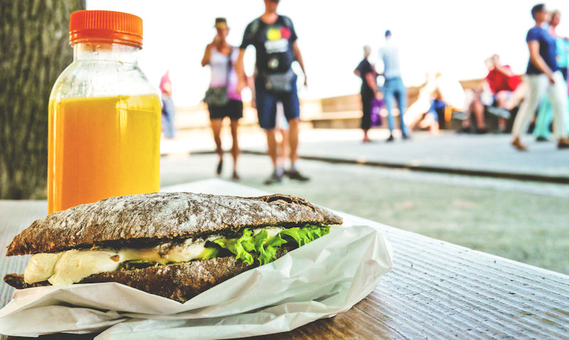 Bottle of orange juice served with gourmet sandwich