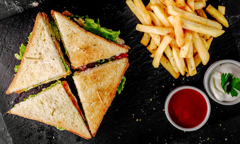 Toasted sandwich served with ketchup, mayonnaise, potato chips